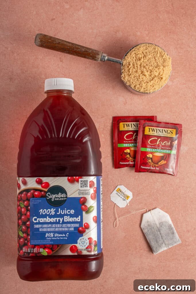 Ingredients for making cranberry chai mocktail laid out on a pick background.