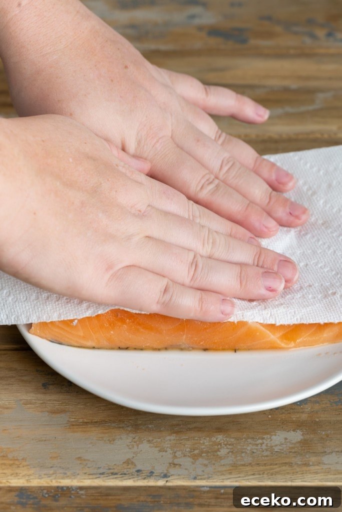 patting salmon dry with paper towel to reduce excess moisture