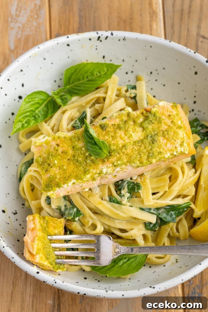 close up of pesto butter salmon over pasta with a forkful