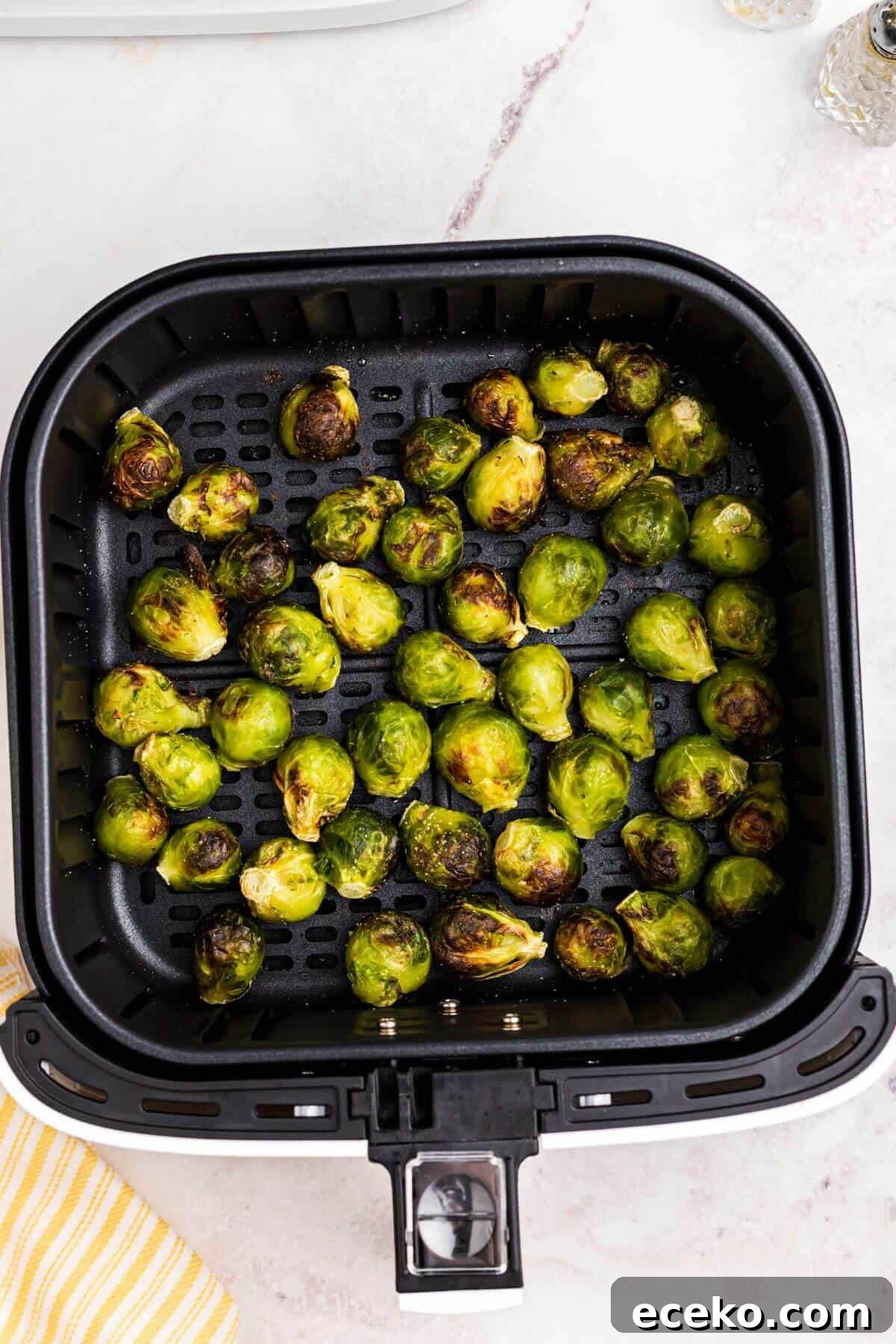 Green juicy brussels sprouts in the air fryer basket after being cooked. 