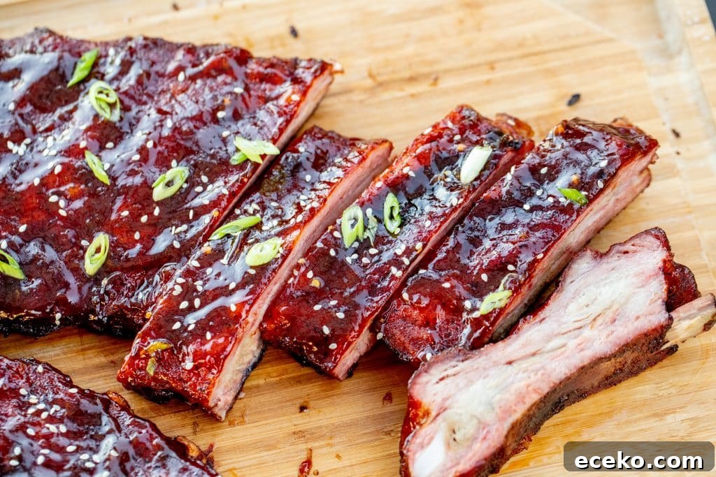 Sliced orange glazed ribs on a wooden cutting board.