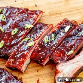 Sliced orange glazed ribs on a wooden cutting board.