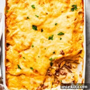 Overhead image of hamburger potato casserole in a baking dish, with a serving of it missing from the corner.