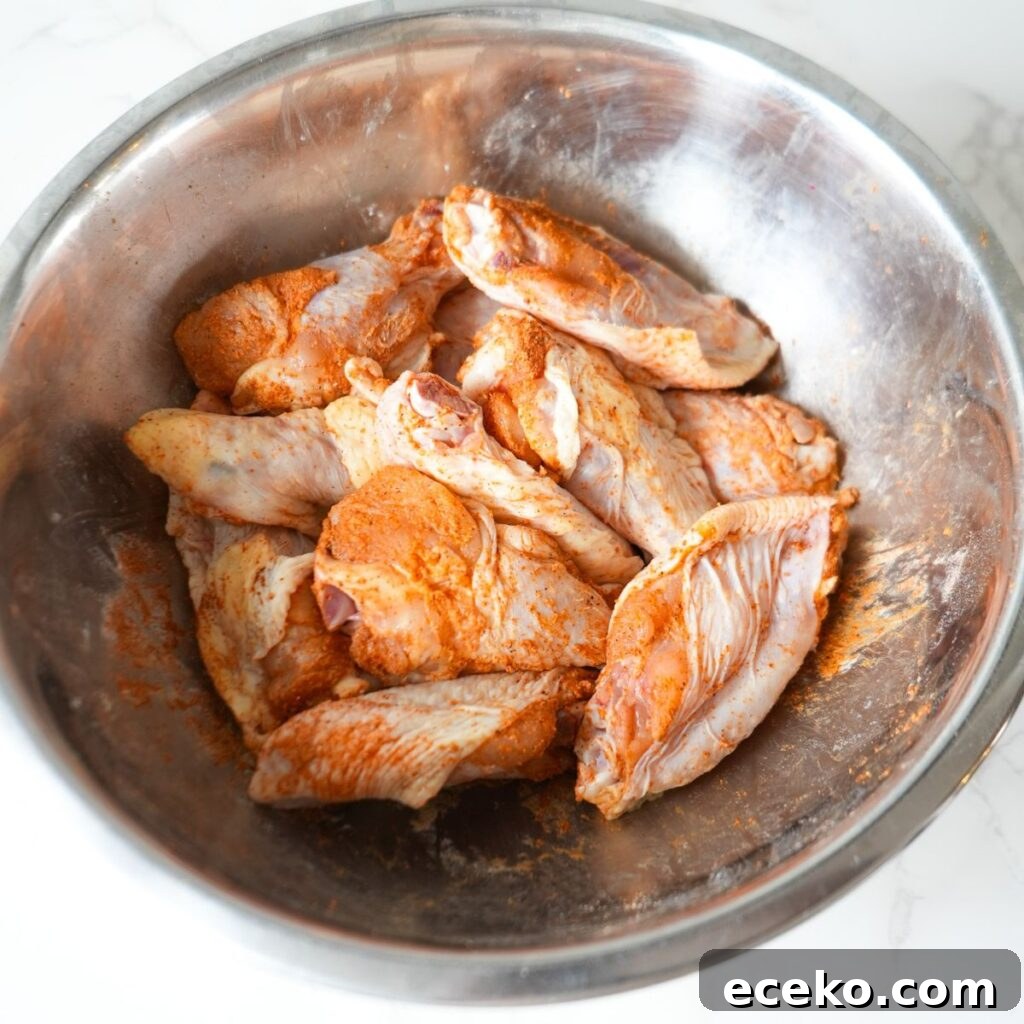 Raw wings in a bowl with seasoning.