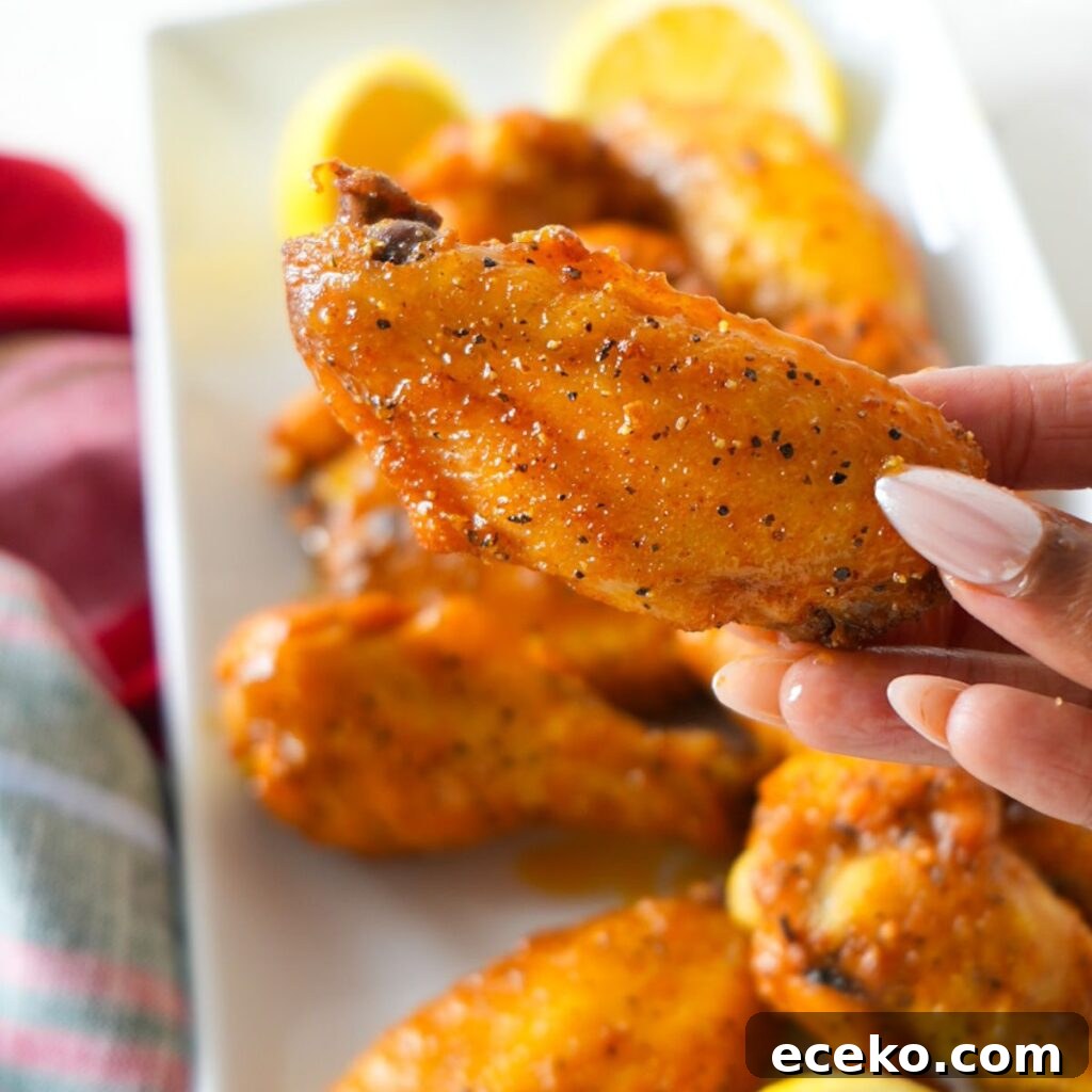 Oven-baked lemon pepper wings coated in a zesty buttery sauce, served with lemon slices.