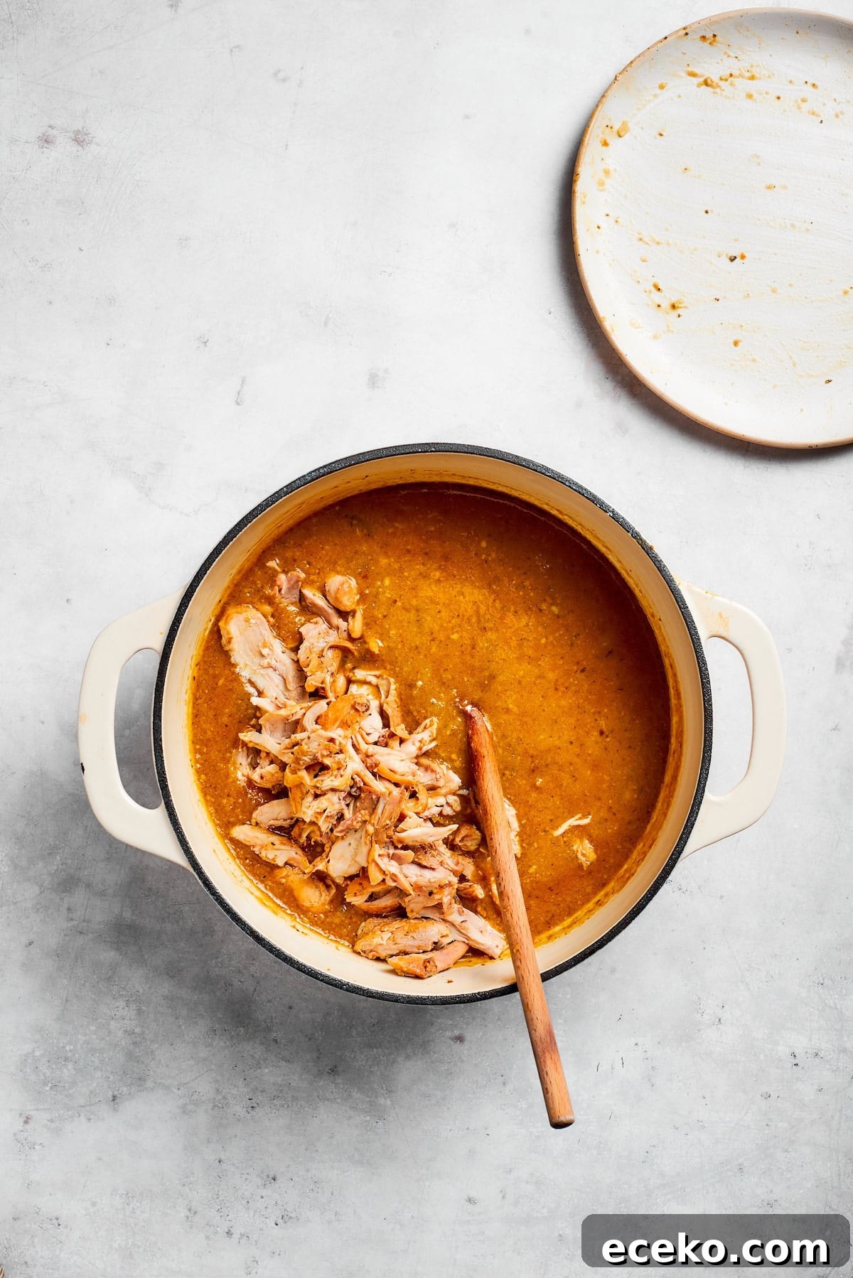 Return the shredded chicken to the soup. Chicken is added back into a soup pot.