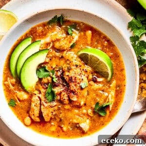 Zesty Spicy Chicken Soup Recipe with Lime and Garlic 2 Spicy chicken soup in a bowl garnished with avocado slices and lemon wedges.