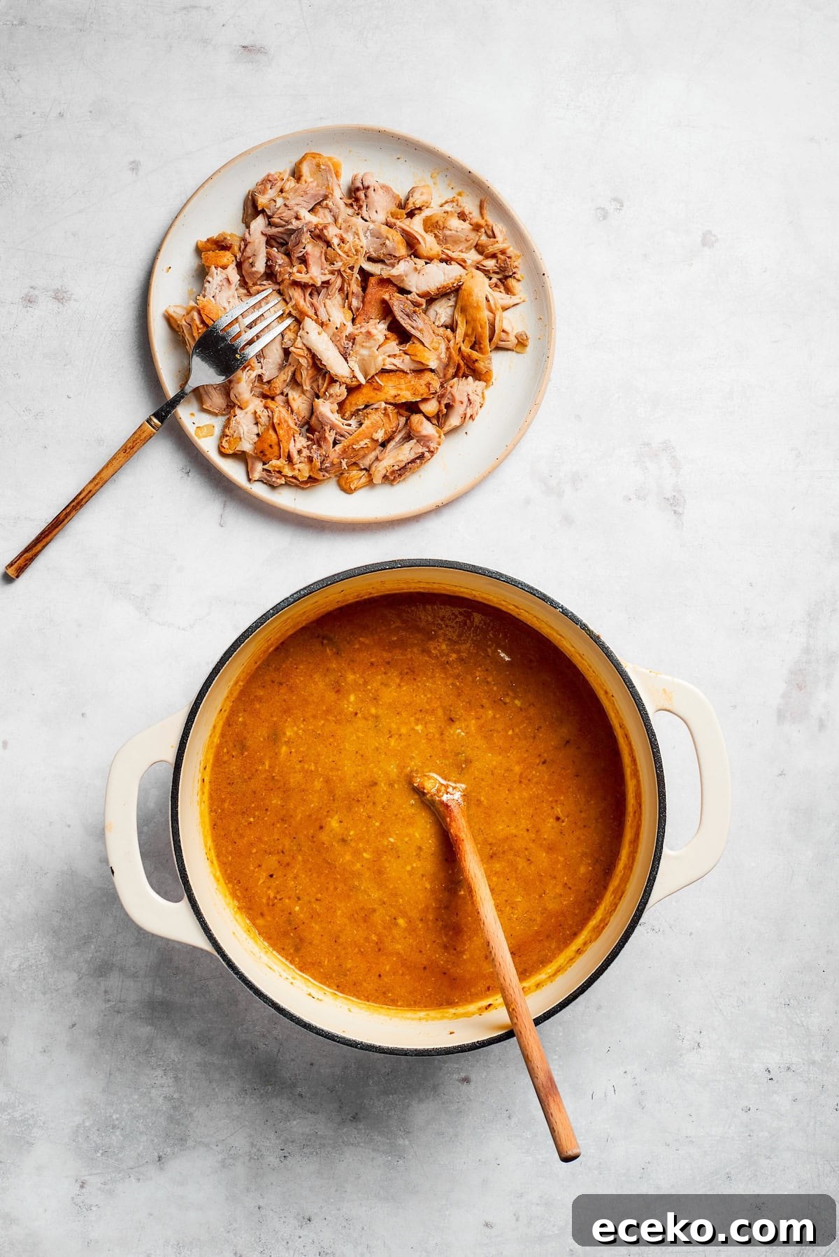 Shred the cooked chicken and return to the pot. A plate of shredded chicken next to a pot of soup.