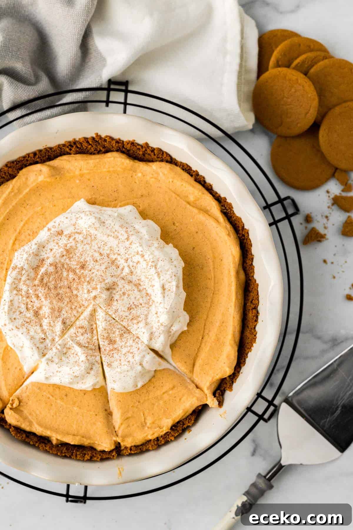Gingersnap Crust Pumpkin Mousse Pie: Creamy Autumn Dessert 2 pumpkin mousse pie in white pie dish on black cooling rack with pie server and gingersnap cookies