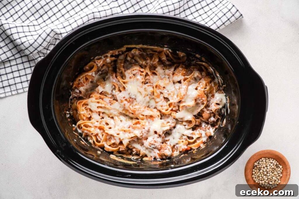 slow cooker with ground beef and noodles topped with cheese