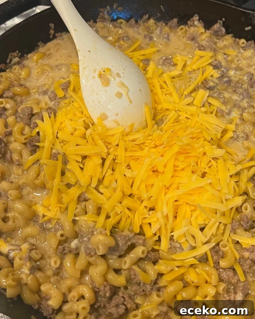 stir shredded cheddar cheese with hamburger mixture.