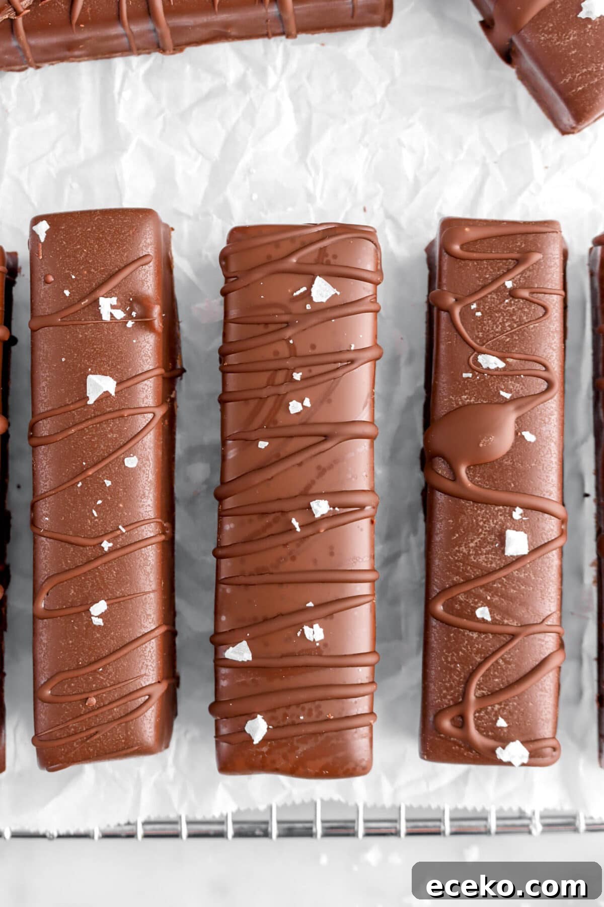Homemade Twix Bars Recipe: Crispy Caramel Chocolate Cookies 3 close up overhead shot of three chocolate coated candy bars with flaked salt