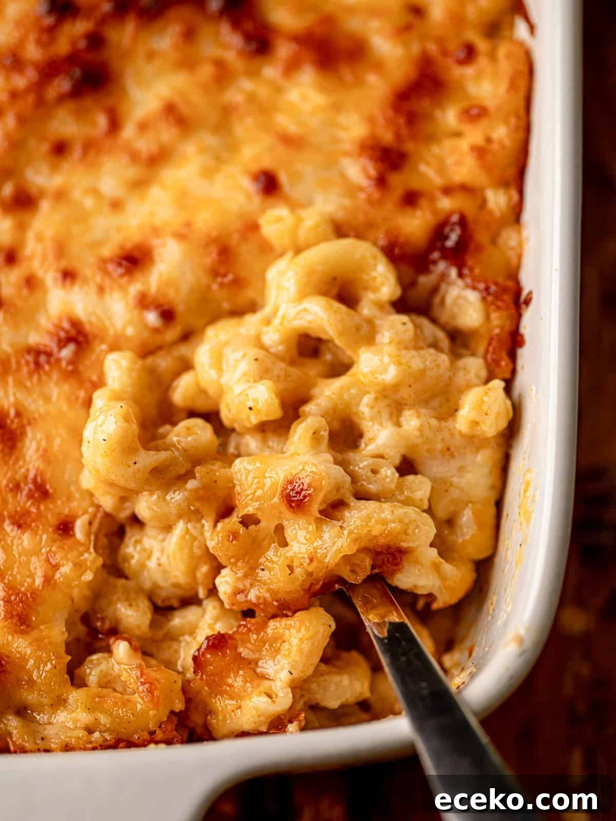 A spoon in a pan of mac and cheese.