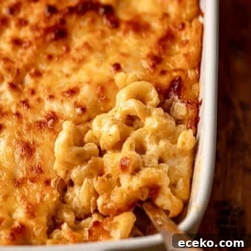 A spoon scooping into a pan of mac and cheese.