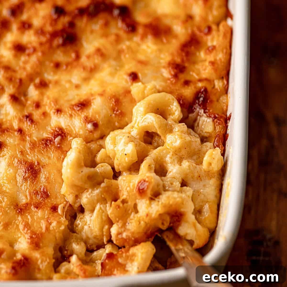 A spoon scooping into a pan of mac and cheese.