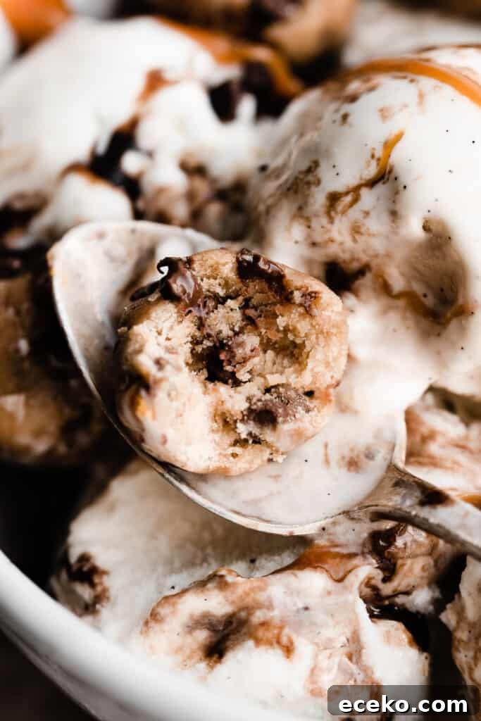 No-Bake Edible Cookie Dough Bites Recipe for Parties 11 A spoon with a cookie dough bite that has a bite taken out of it, resting in a bowl of ice cream.