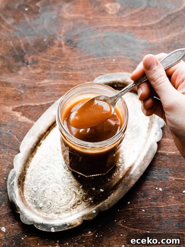 No-Bake Edible Cookie Dough Bites Recipe for Parties 15 A spoon dipping into a jar of caramel sauce.