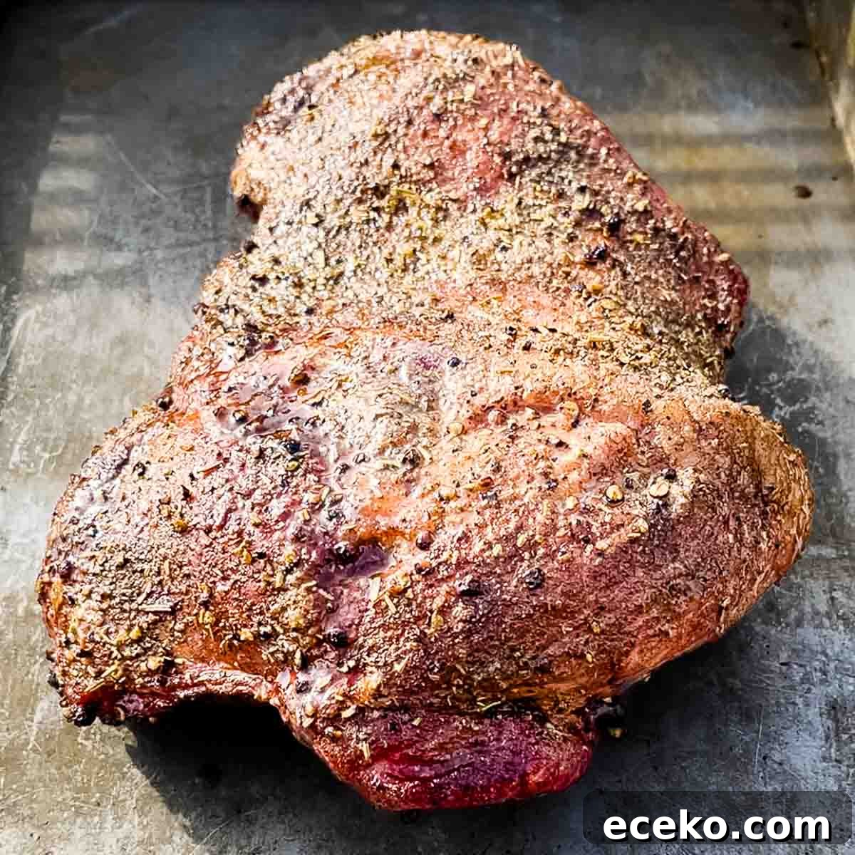 Boneless Smoked Leg of Lamb on a Pellet Grill — Tender Recipe 9 The smoked leg of lamb removed from the pellet grill and placed on a baking sheet to rest.