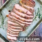 Boneless Smoked Leg of Lamb on a Pellet Grill — Tender Recipe 17 Smoked boneless leg of lamb sliced and placed on a baking sheet with sprigs of fresh rosemary beside it.