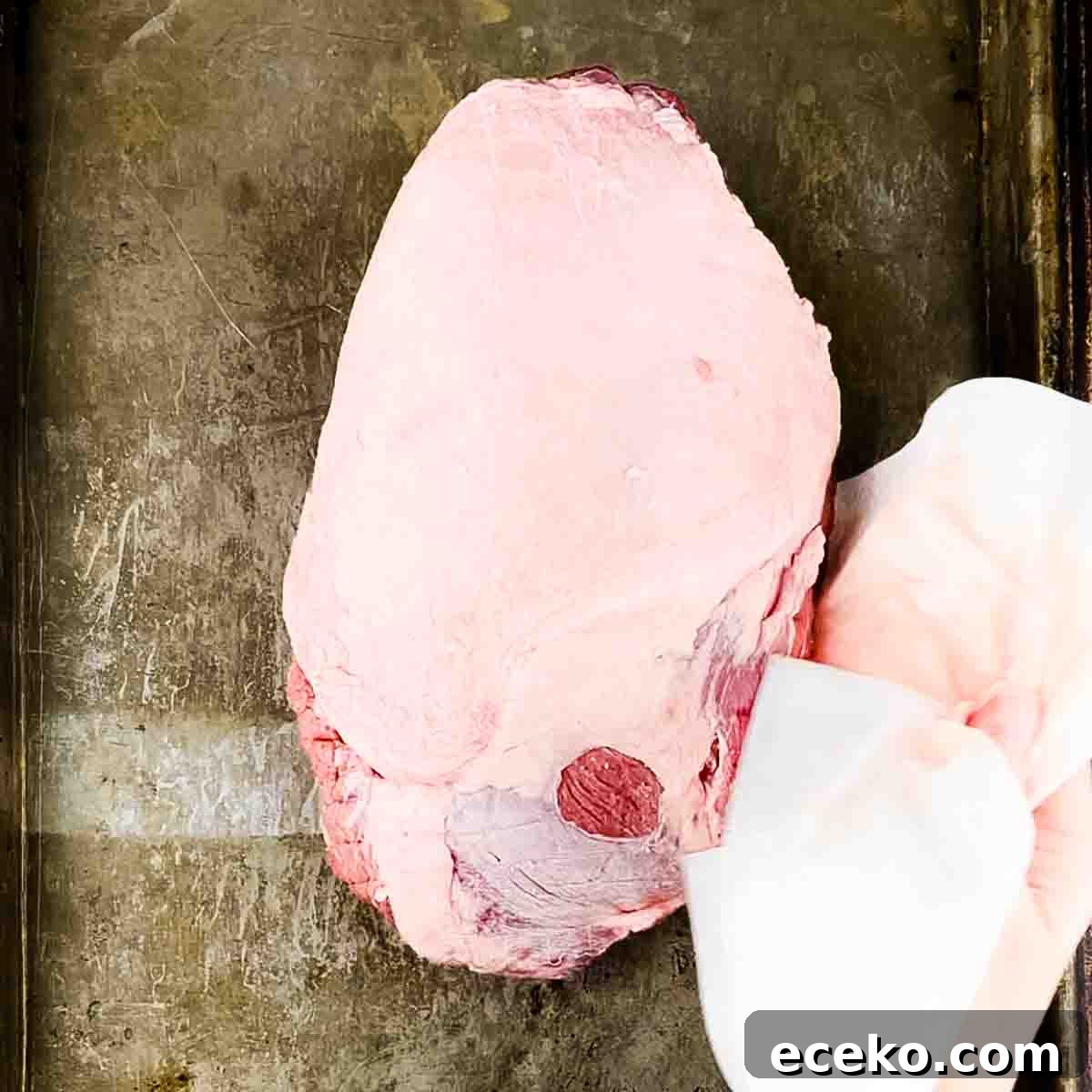 Boneless Smoked Leg of Lamb on a Pellet Grill — Tender Recipe 5 The leg of lamb is being patted dry with a paper towel.