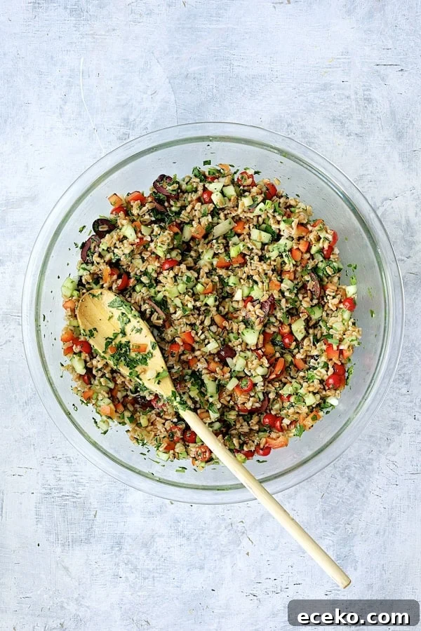 Photo of salad in glass mixing bowl mixed together with white spoon.