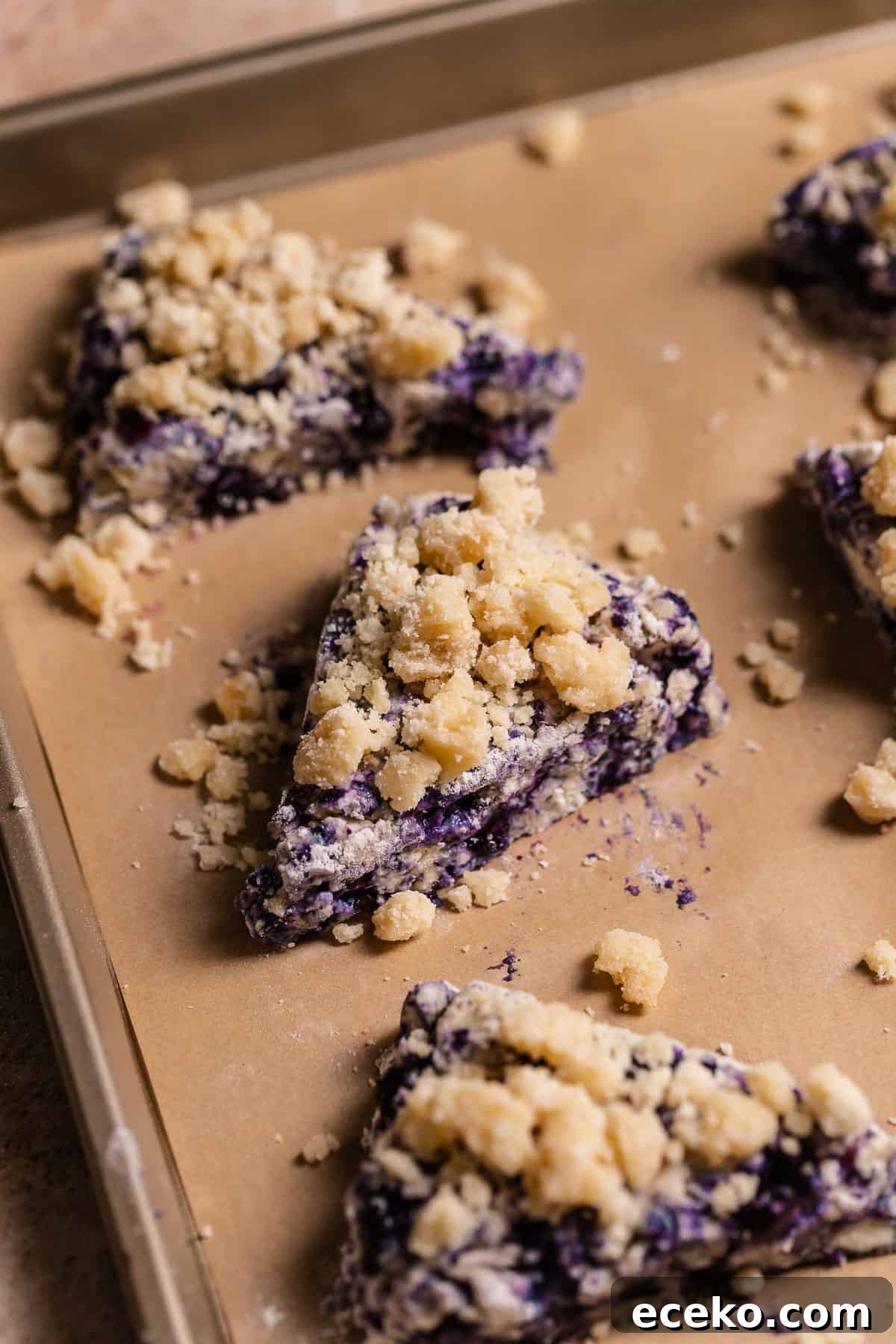 Blueberry scones with crumb topping on a baking sheet.