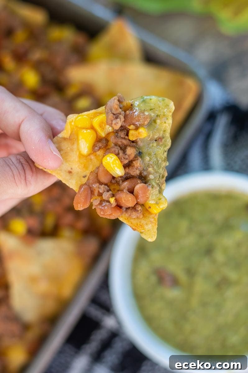 Gluten Free Baked Bean Nachos in someones hand with sauce