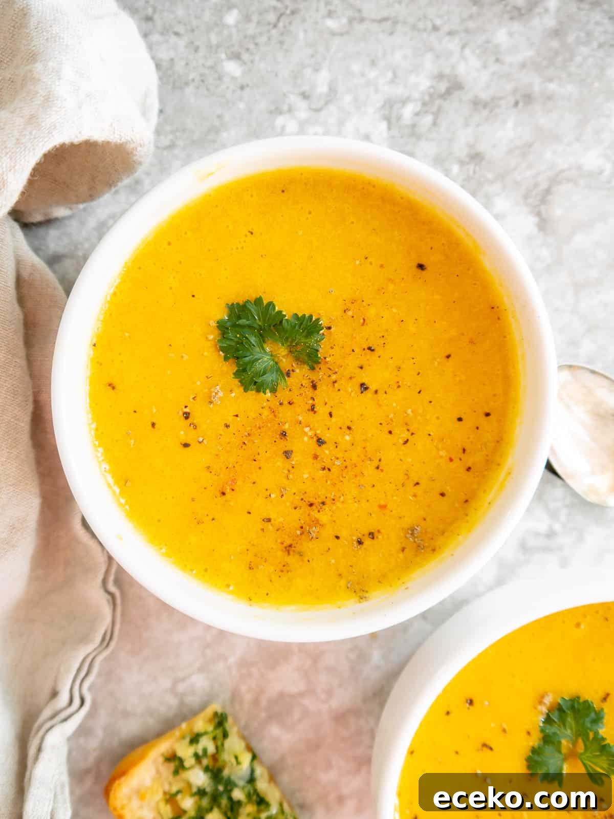 Roasted butternut squash soup in two bowls with parsley on top.