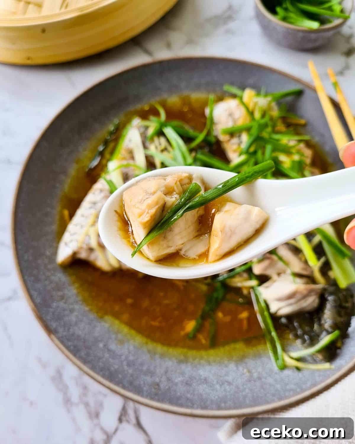 A close up spoonful of steamed fish with delicious ginger and spring onion sauce