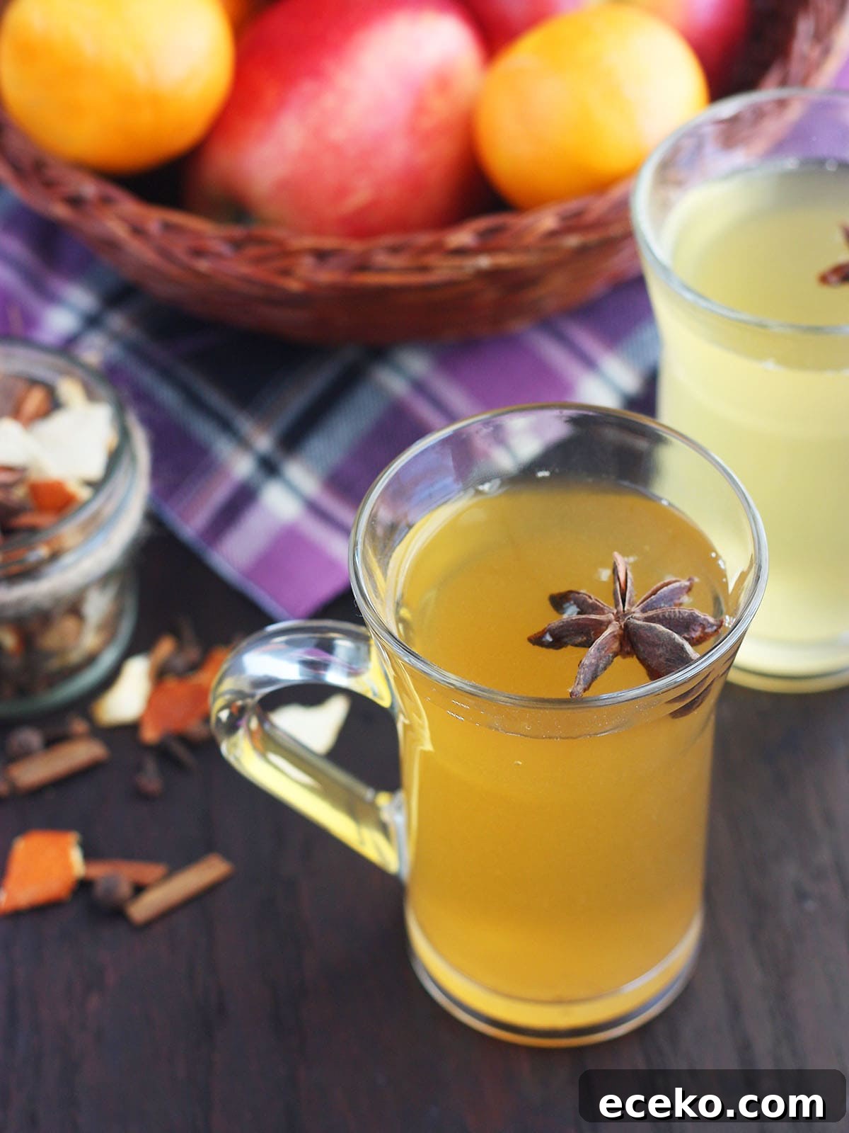Glass mug of mulled apple cider with a whole star anise added as garnish.