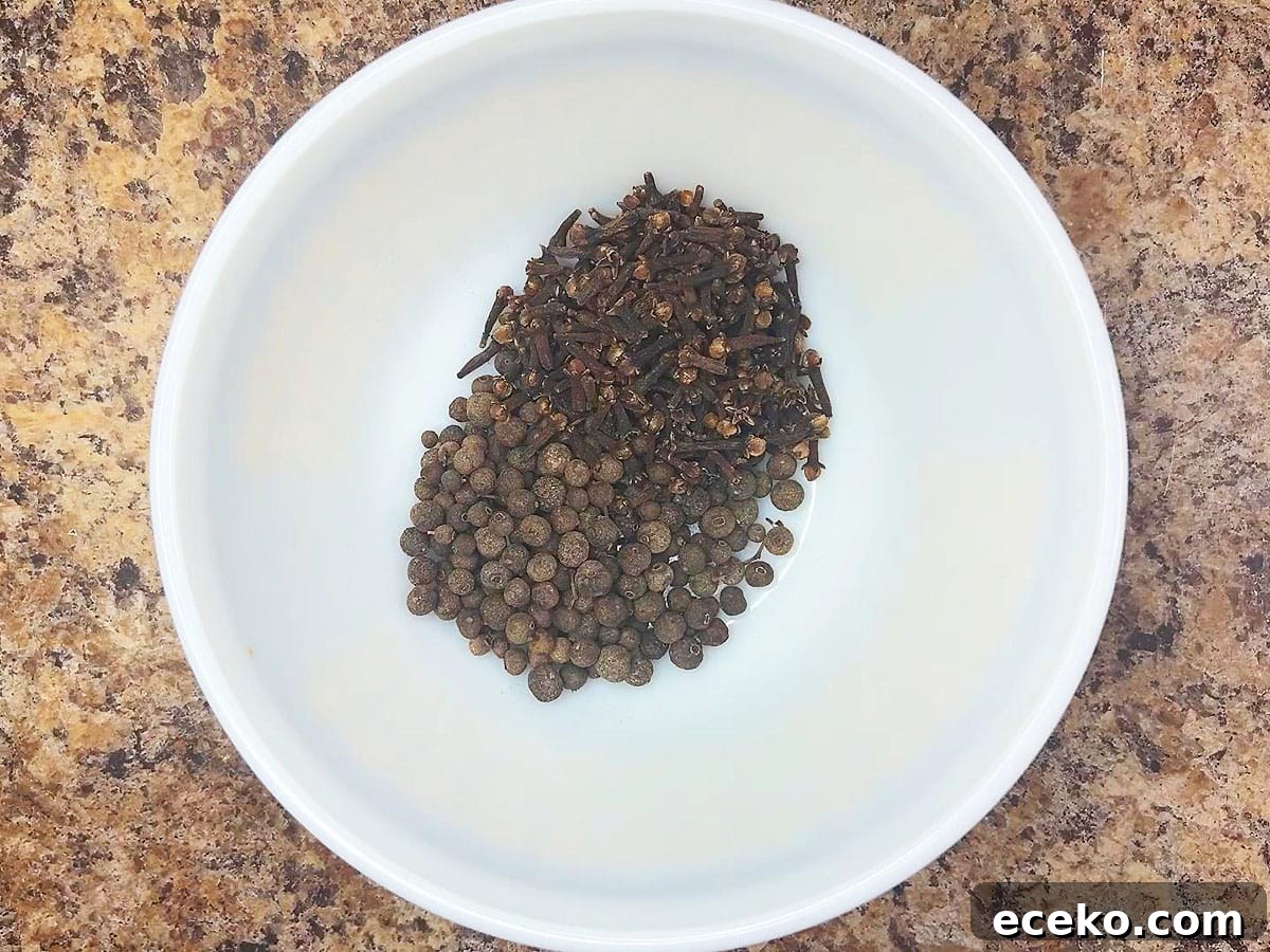 Whole allspice berries and cloves in a small mixing bowl.