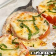 This is a square close-up picture of a baked tomato with melted cheese.