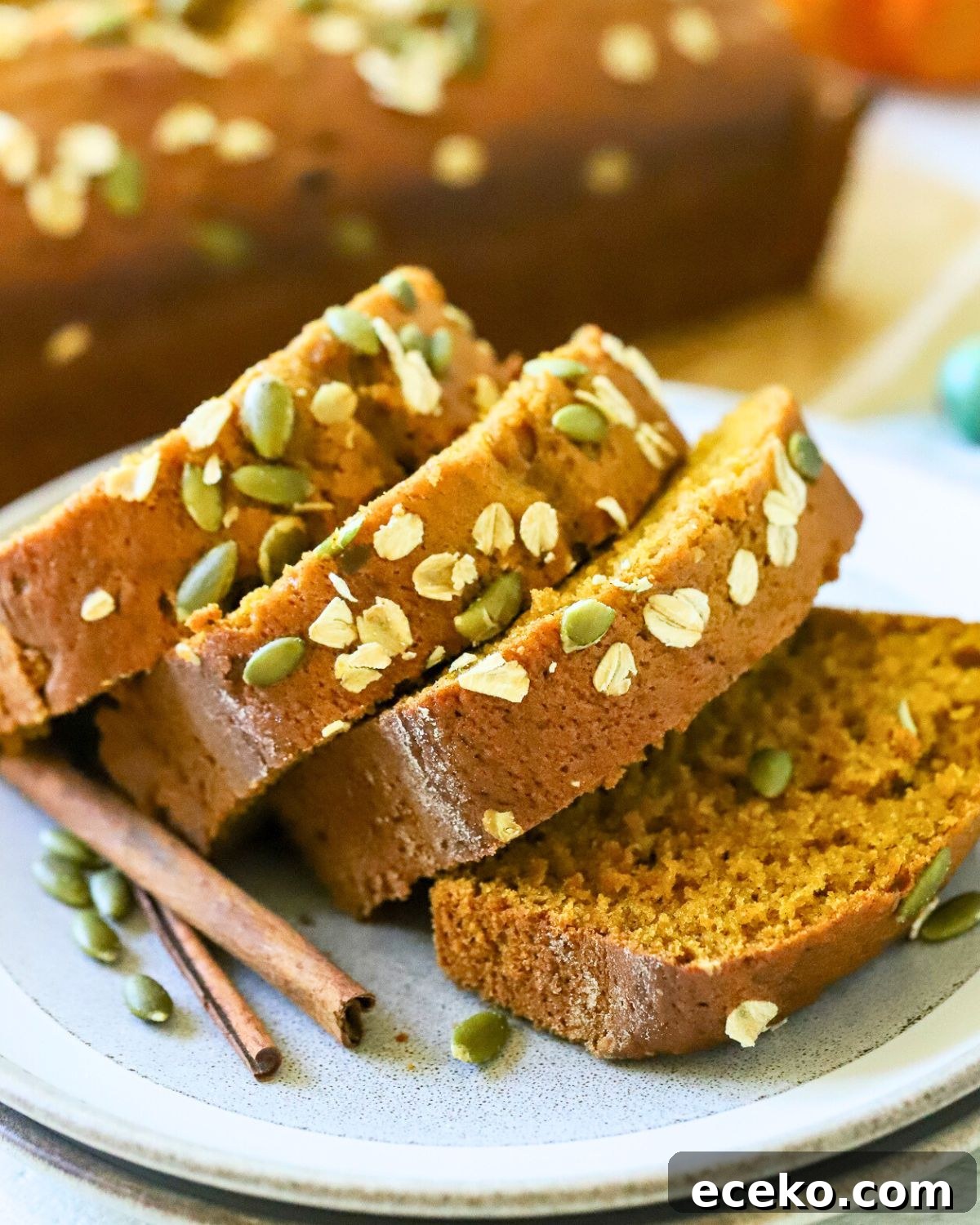 Sliced pumpkin bread with pumpkin seeds on top.