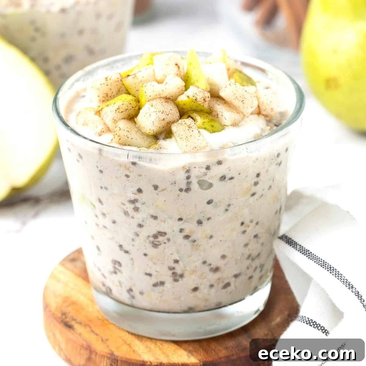 Glass of cinnamon overnight oats, topped with some chunks of fresh pear.