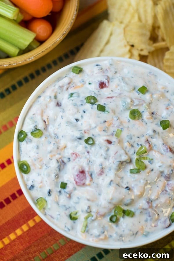 Southwestern Ranch Dip in a white bowl next to chips and veggies.