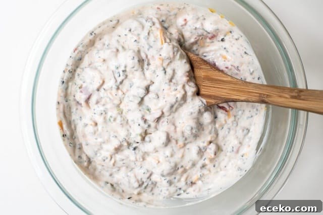 Dip ingredients mixed together in a bowl with a wooden spoon.