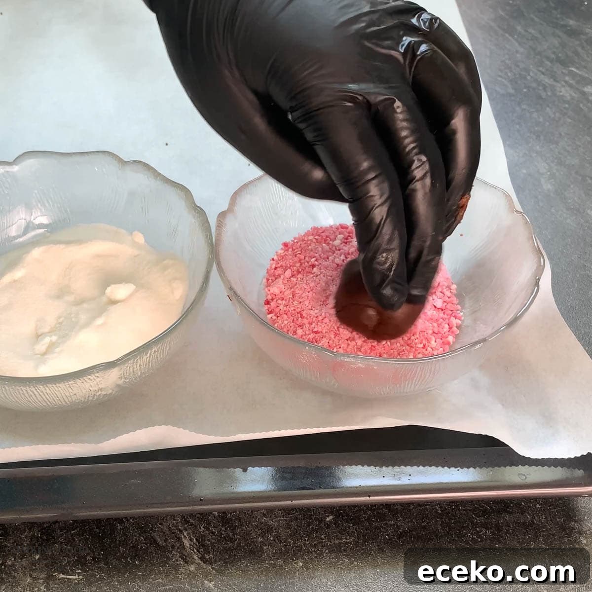 Chocolate Peppermint Crinkle Cookies Recipe for the Holidays 11 Hand with black gloves holding dough ball over a bowl filled with crushed candy canes.