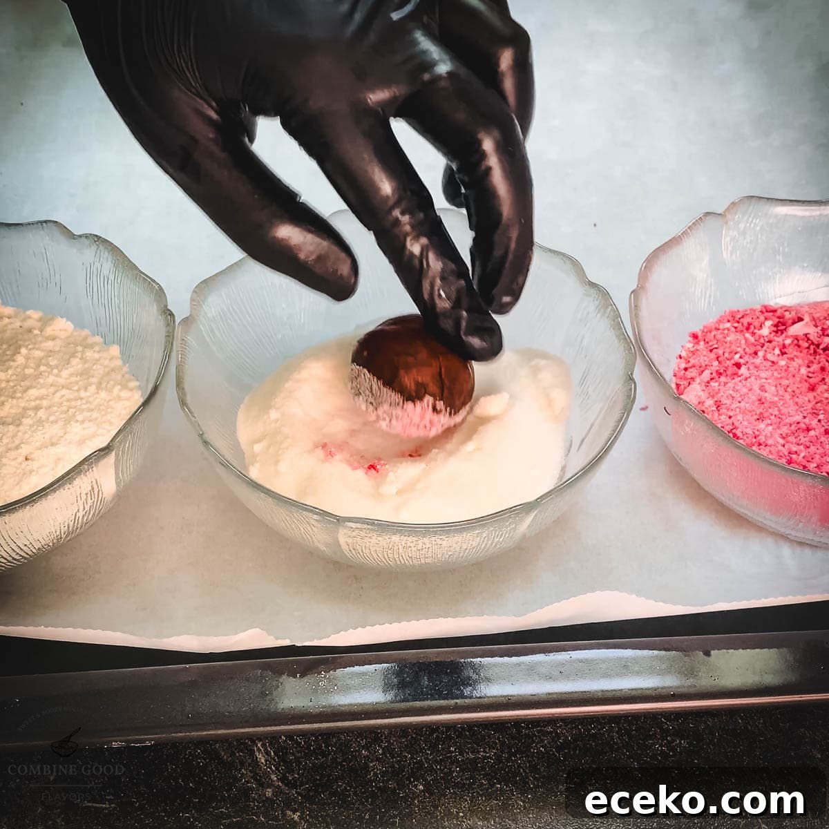 Chocolate Peppermint Crinkle Cookies Recipe for the Holidays 13 Hand with black gloves holding dough ball over a bowl filled with granulated sugar.