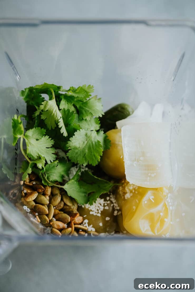 drained salsa verde ingredients added to the base of a blender with fresh cilantro, pepitas, and salt.