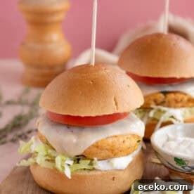 Gluten free chicken burgers on a board with cheese a tomato slice.