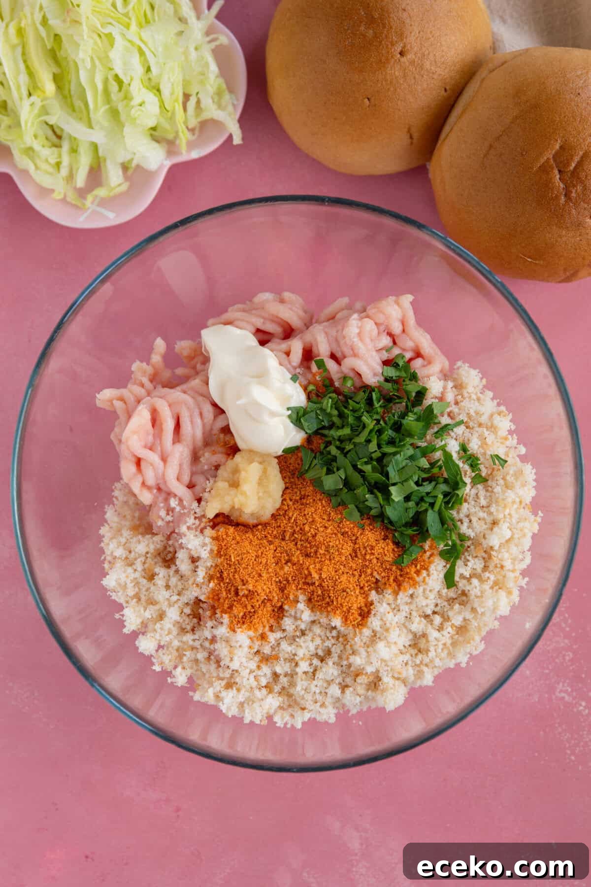 Process shot for chicken mince burgers showing the ingredients added to a glass mixing bowl.