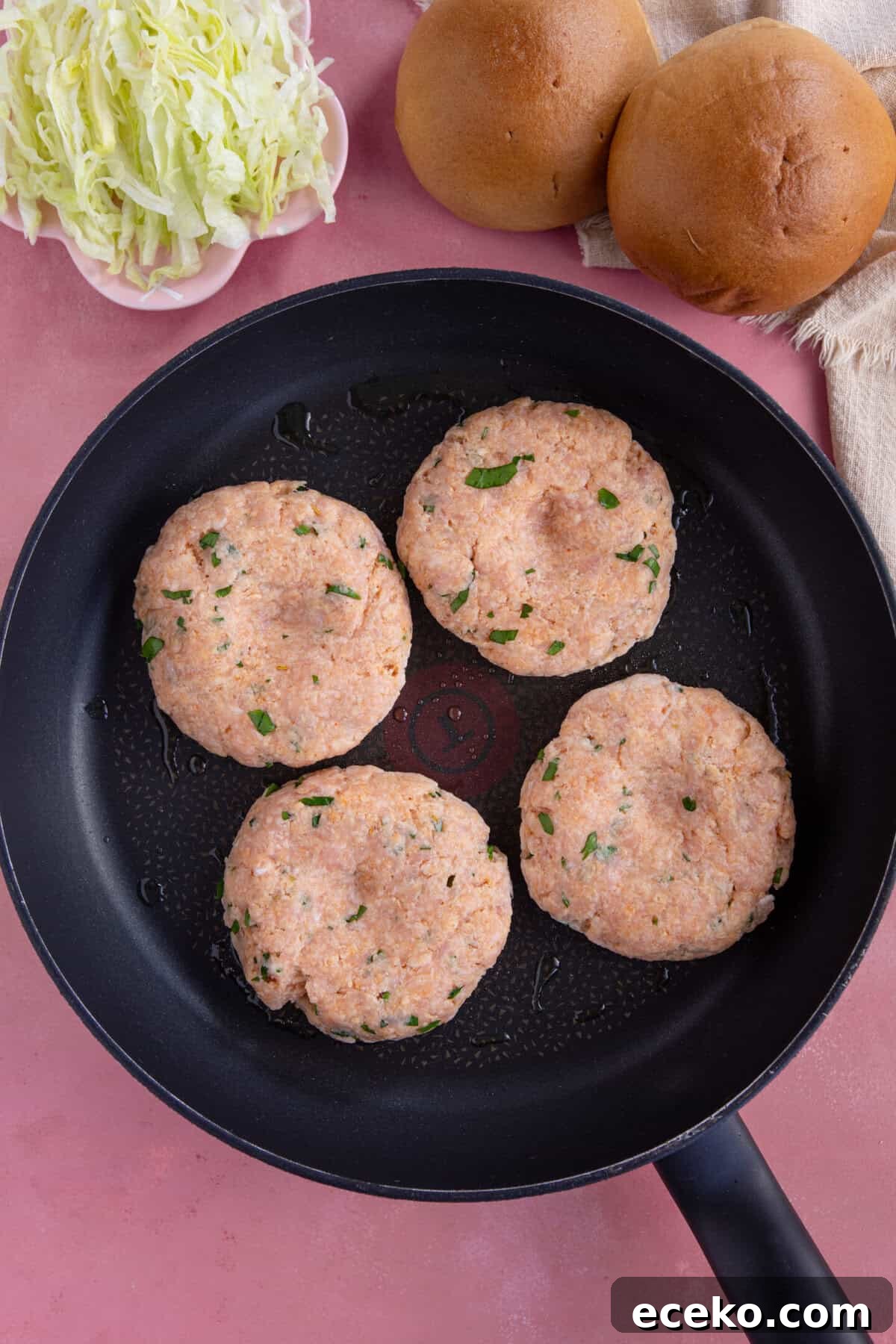Process shot for chicken mince burgers showing the chicken burger patties in a pan.