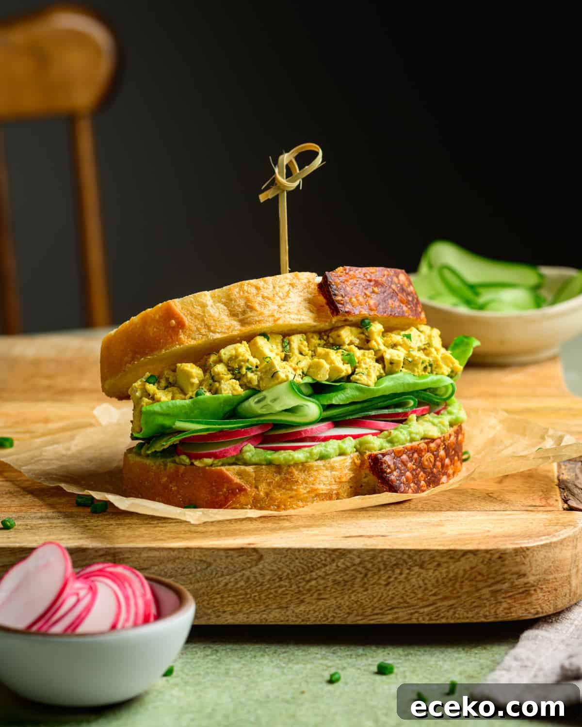 Vegan egg salad sandwich on a wooden cutting board on a table.