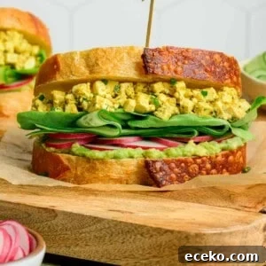 side view of egg salad sandwich on a wooden cutting board.