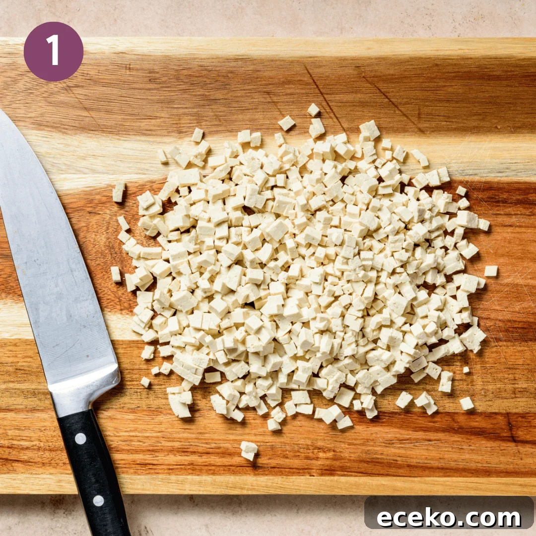 tofu cut into small pieces on a wooden cutting board.
