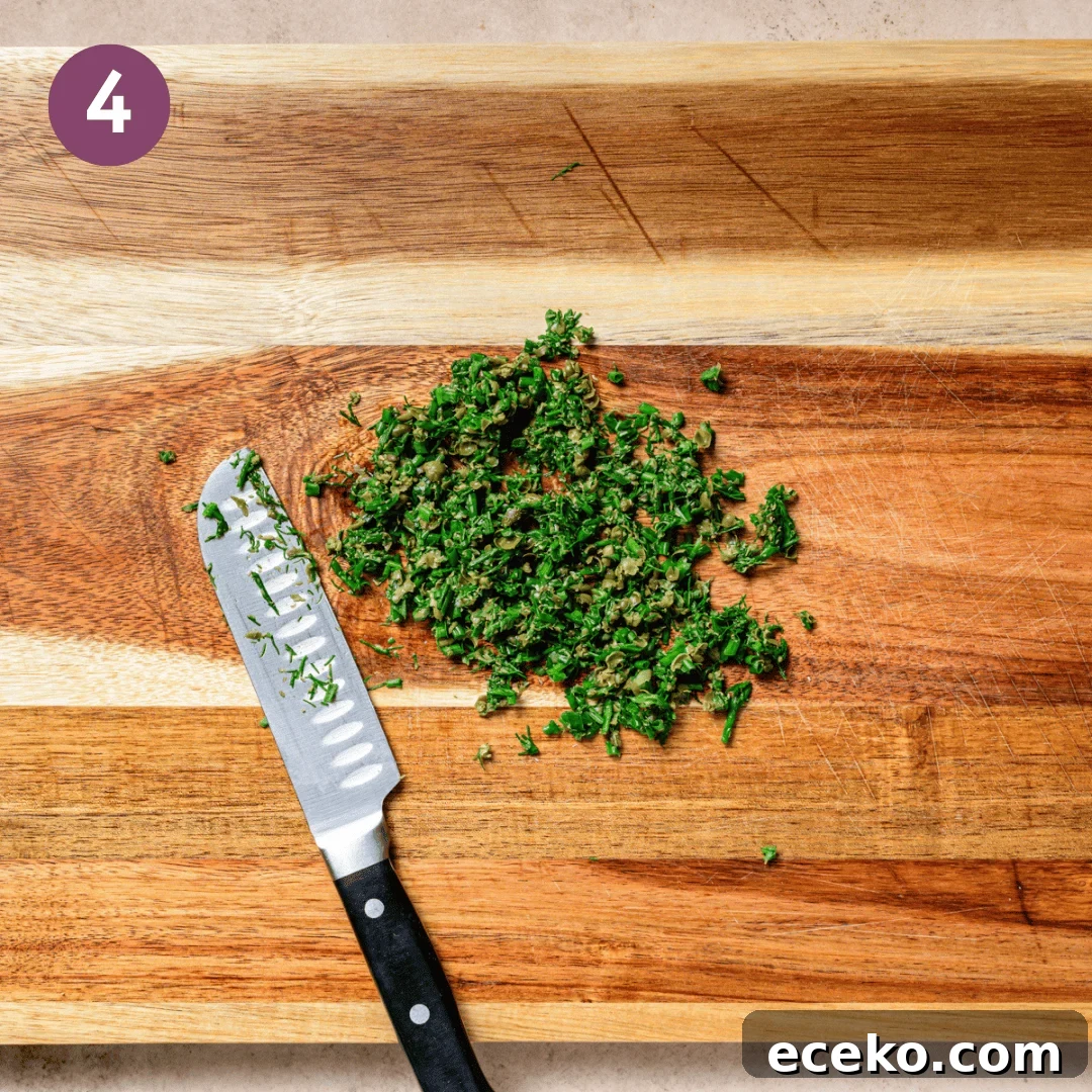chopped herbs and a knife on a wooden cutting board.