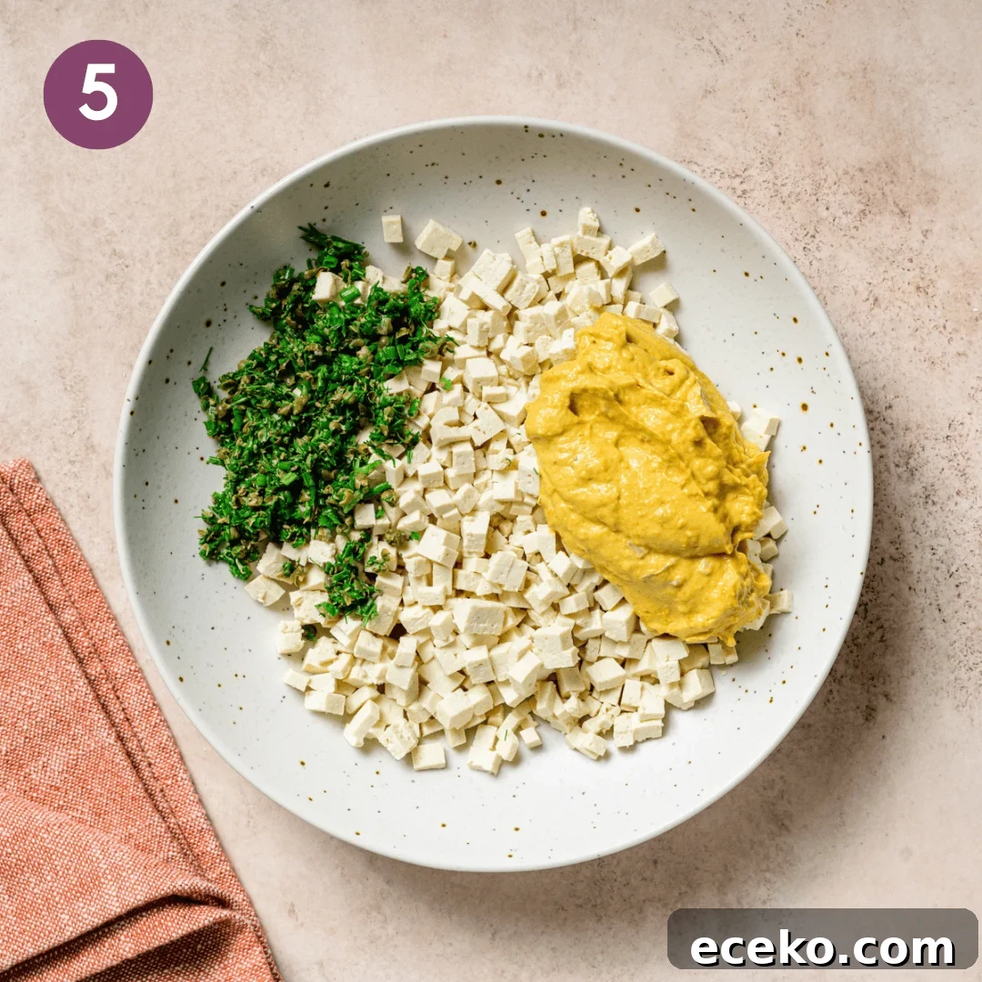 egg salad sauce, tofu and herbs in a bowl before being combined.
