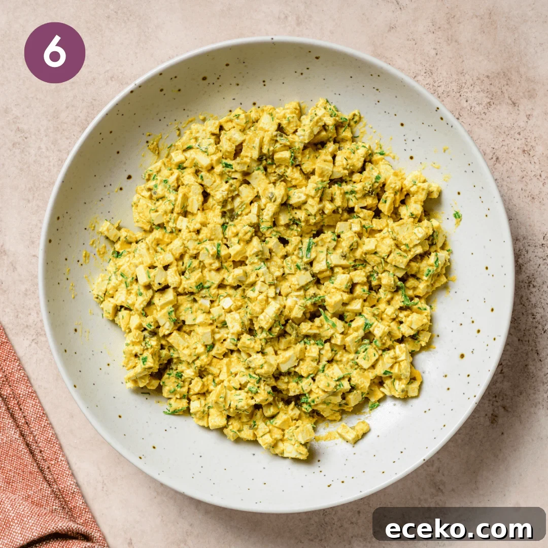 egg salad sauce, tofu and herbs in a bowl after being combined.