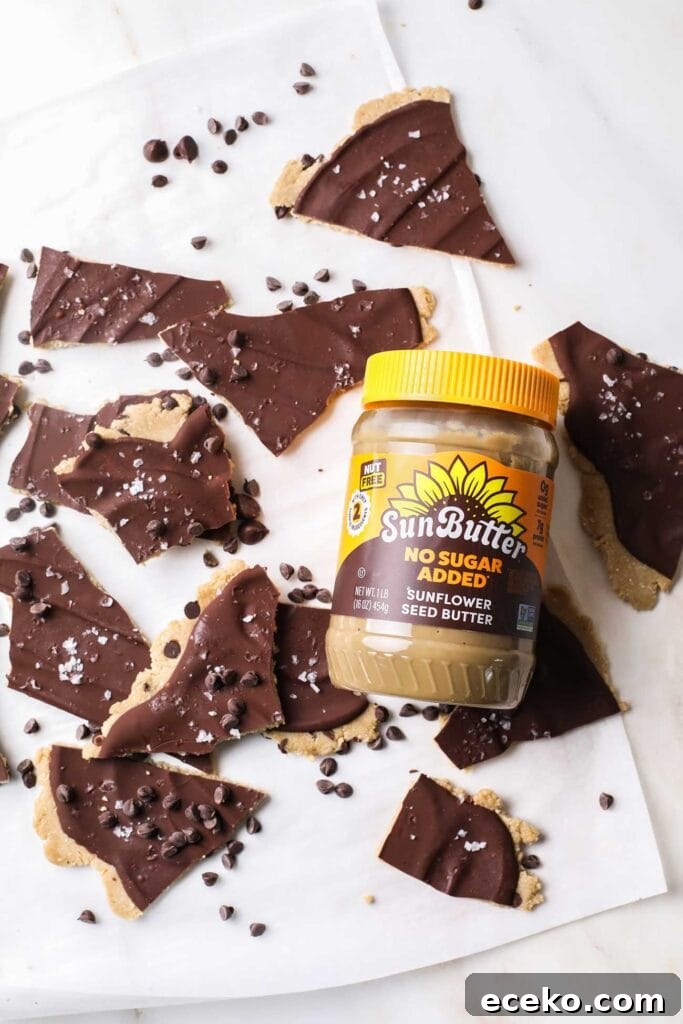 A jar of SunButter sitting next to pieces of cookie dough bark.