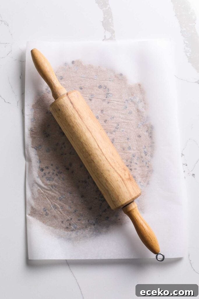 Cookie dough rolled out between two pieces of parchment paper.